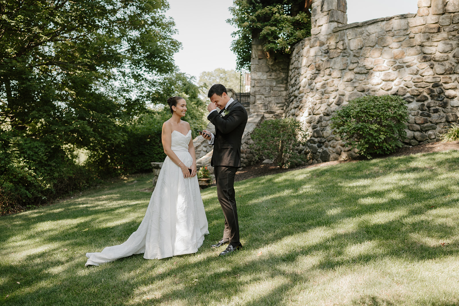 Groom wiping a tear while reading private vows to his smiling bride on the Le Chateau lawn.
